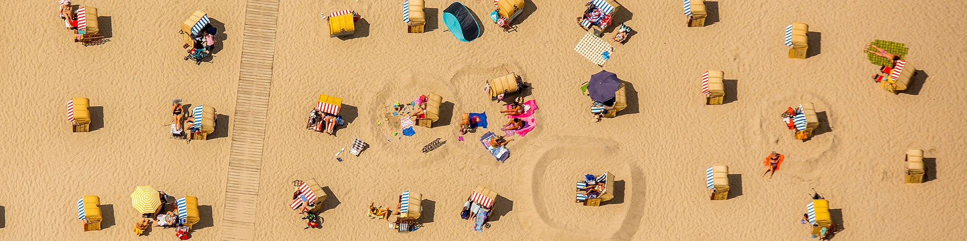 Urlauber und Strandkörbe am Strand zum Thema Tourismus